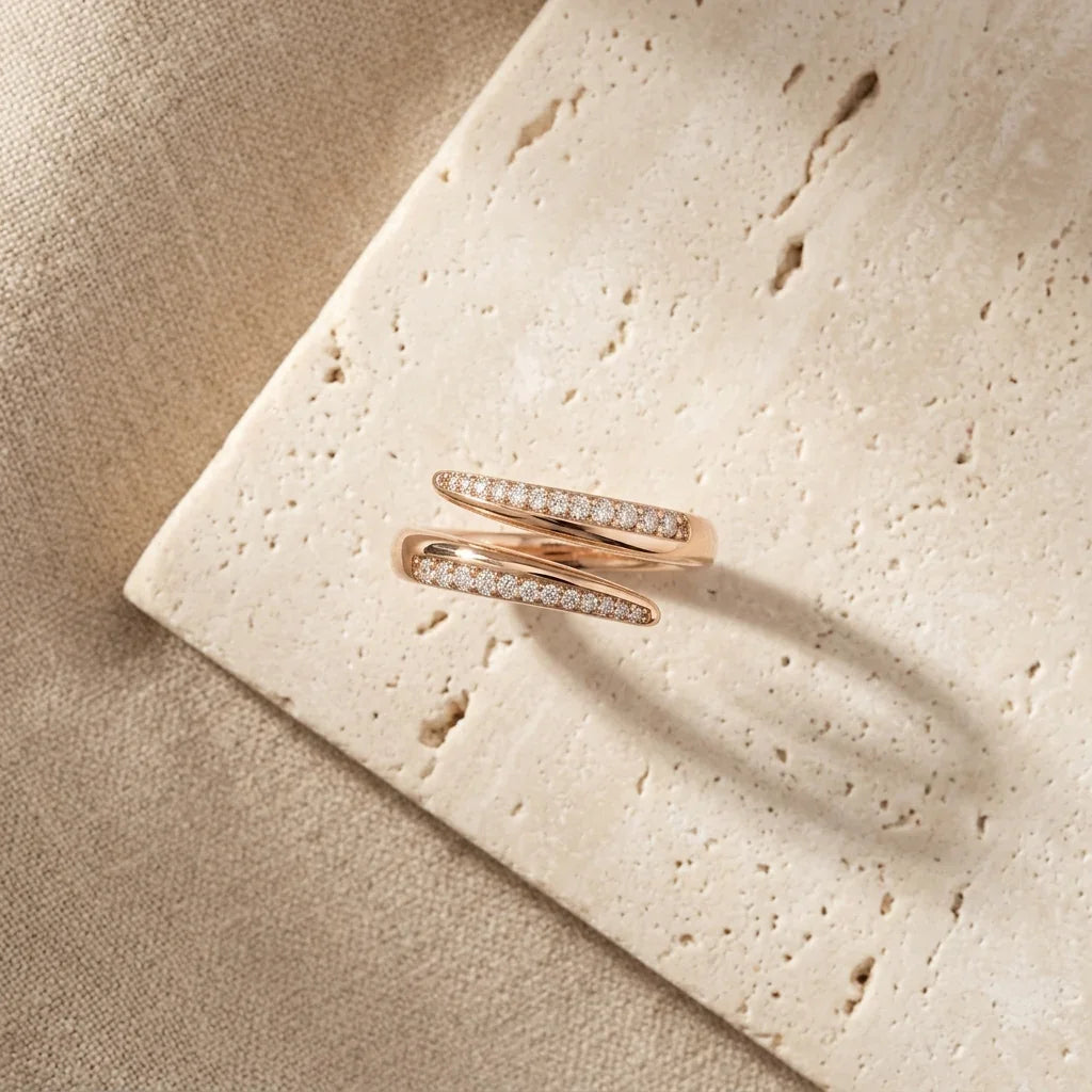 Elegant rose gold diamond ring with intertwined bands, set on textured stone surface