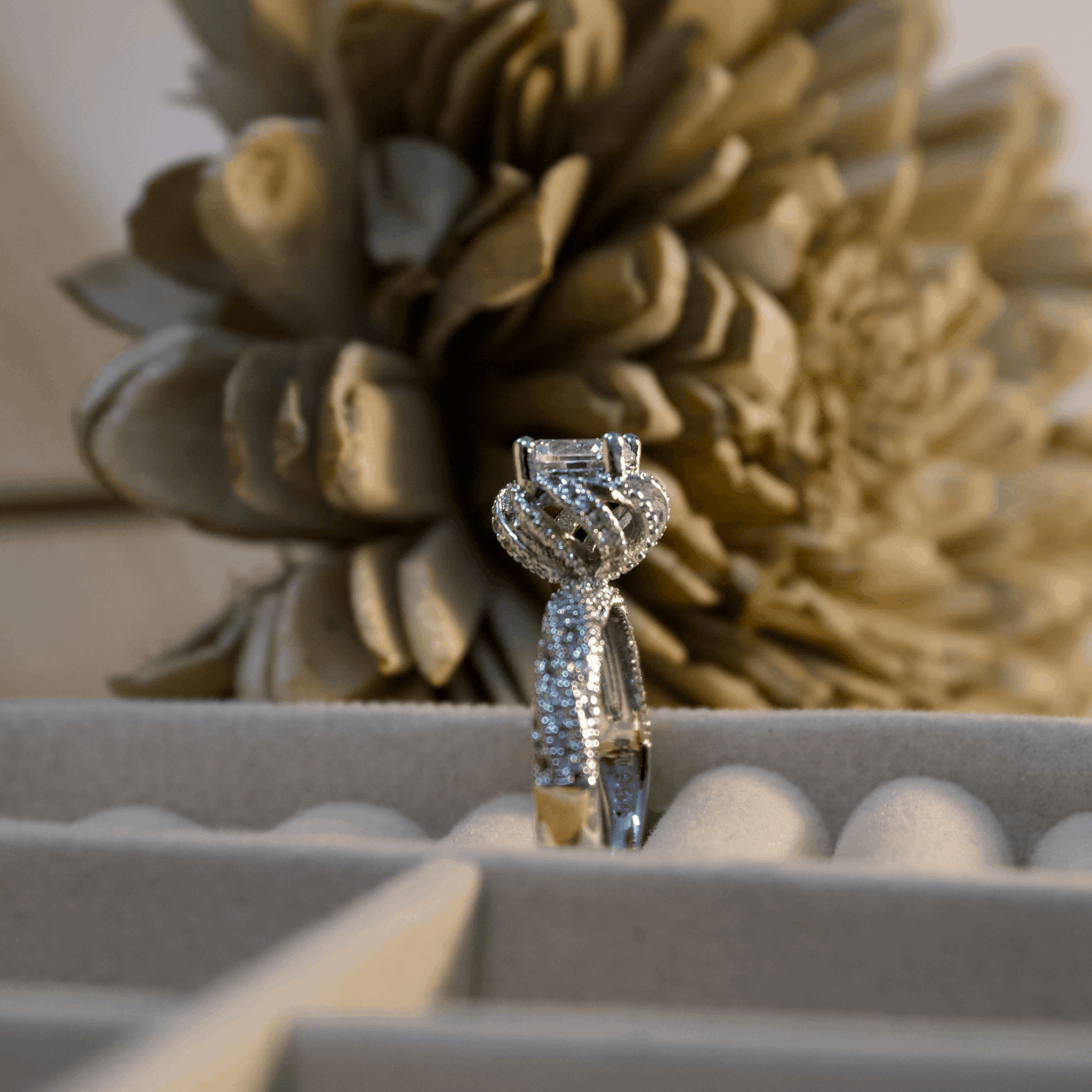 Diamond ring in a box with decorative flowers in the background