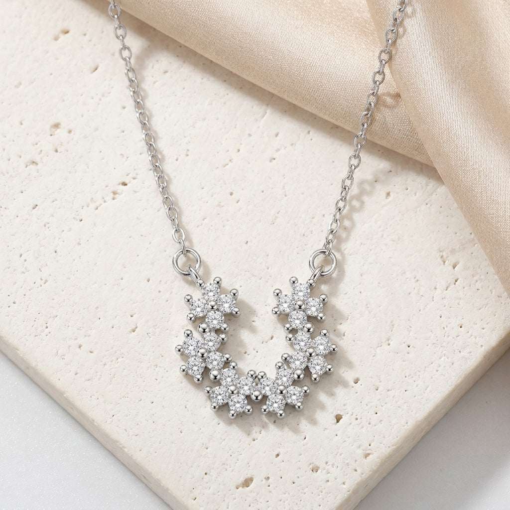 Silver necklace with a floral pendant on a beige fabric background