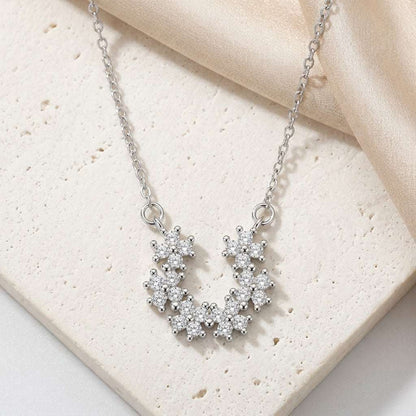 Silver necklace with a floral pendant on a beige fabric background