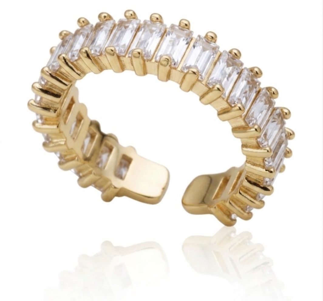 A gold-plated adjustable ring band featuring a row of clear rectangular baguette-cut gemstones, shown on a white background with a soft reflection.