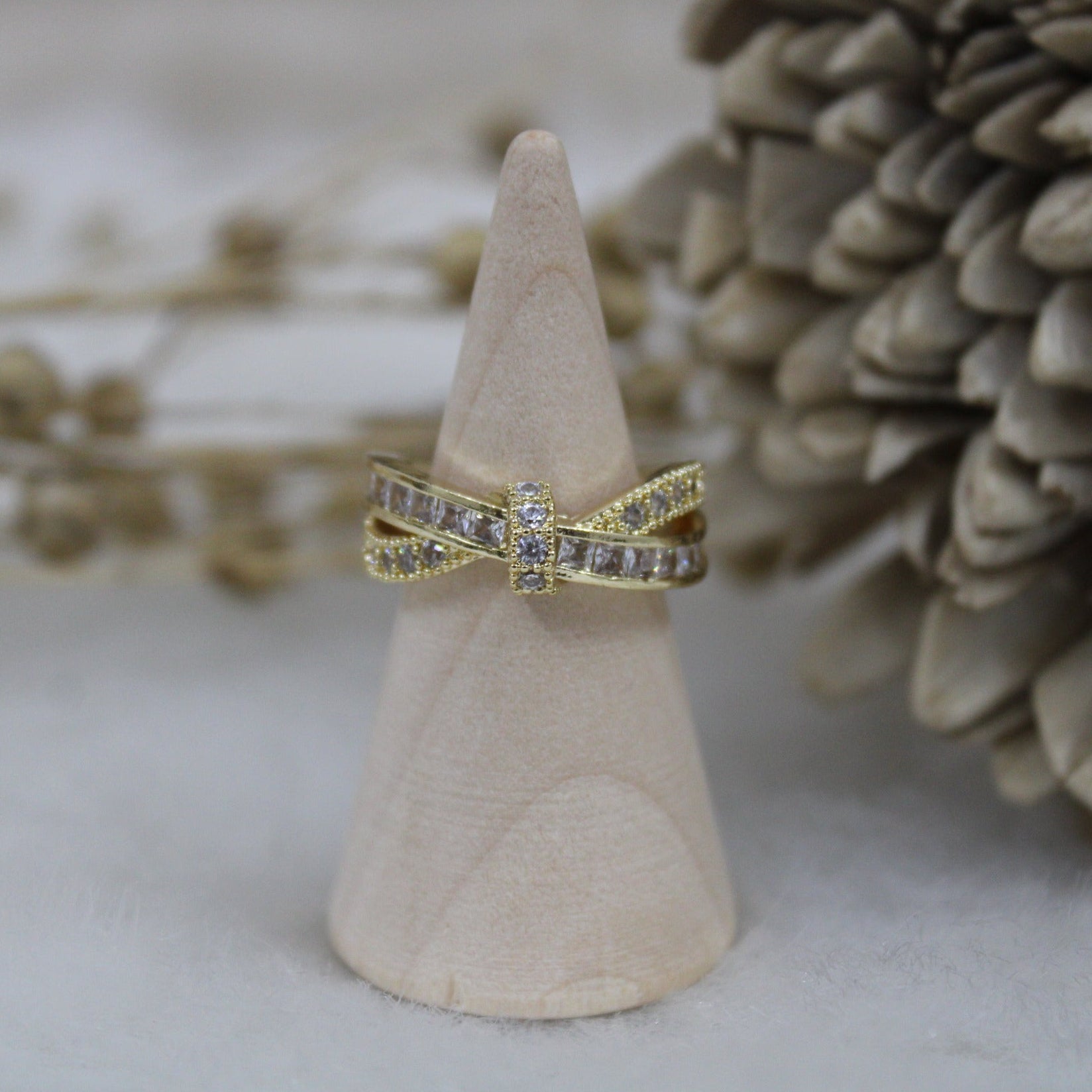 Gold ring with diamond accents on a wooden cone against a natural background