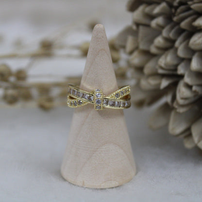 Gold ring with diamond accents on a wooden cone against a natural background