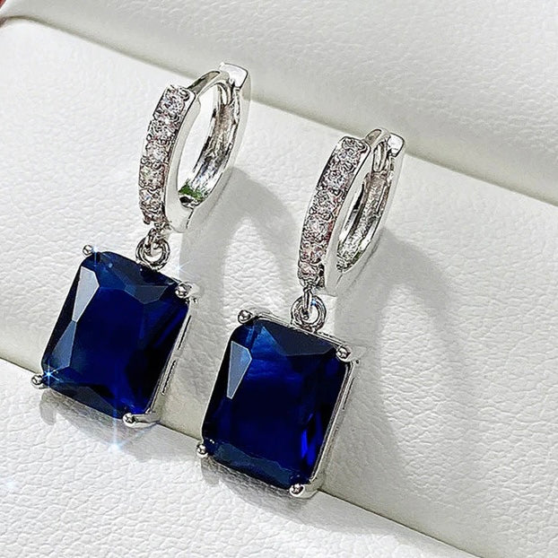 Silver earrings with blue gemstones on a white background