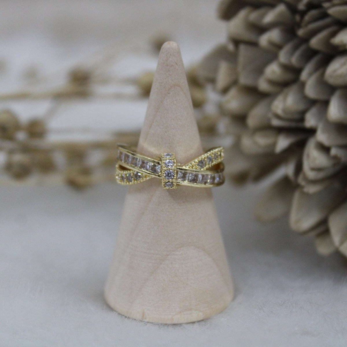 Gold ring with diamond accents on a wooden cone against a natural background