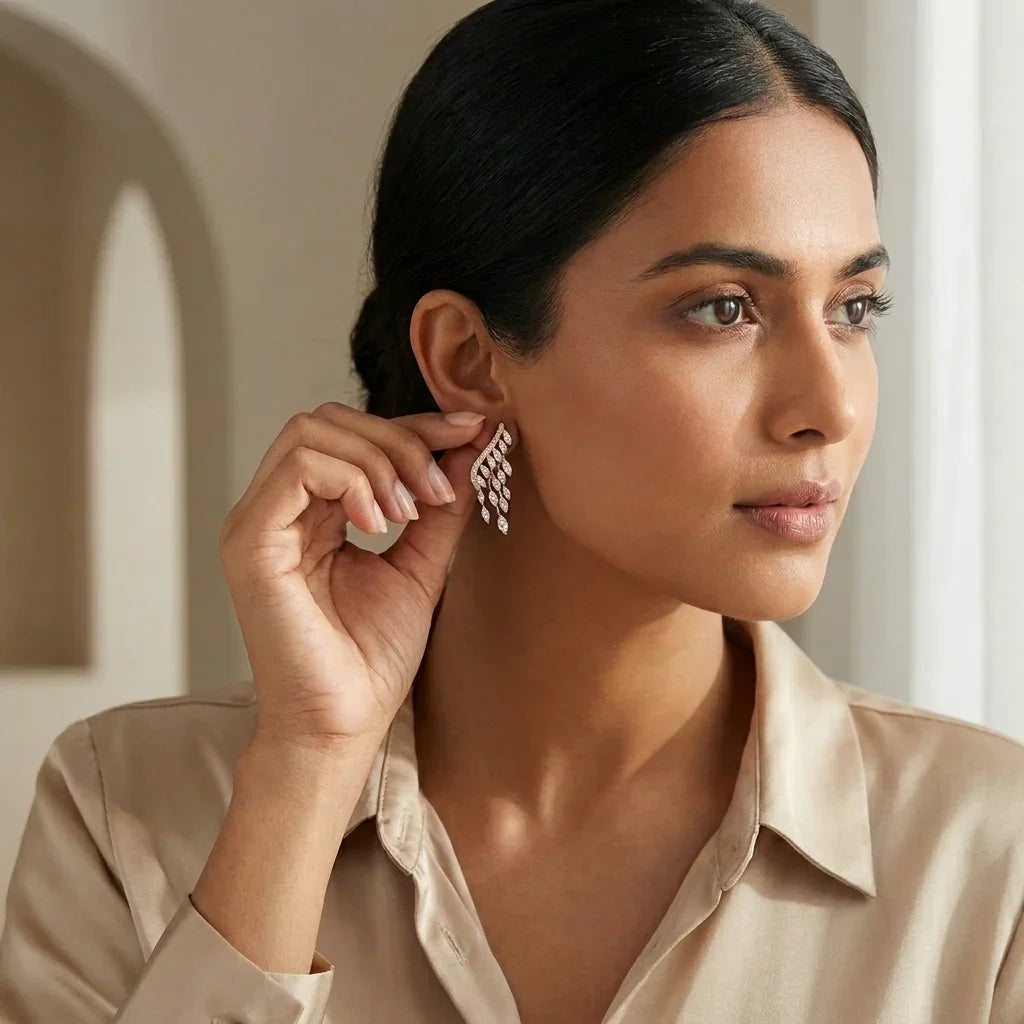 Elegant American Diamond drop earrings with cascading sparkle, worn by woman in soft beige blouse.