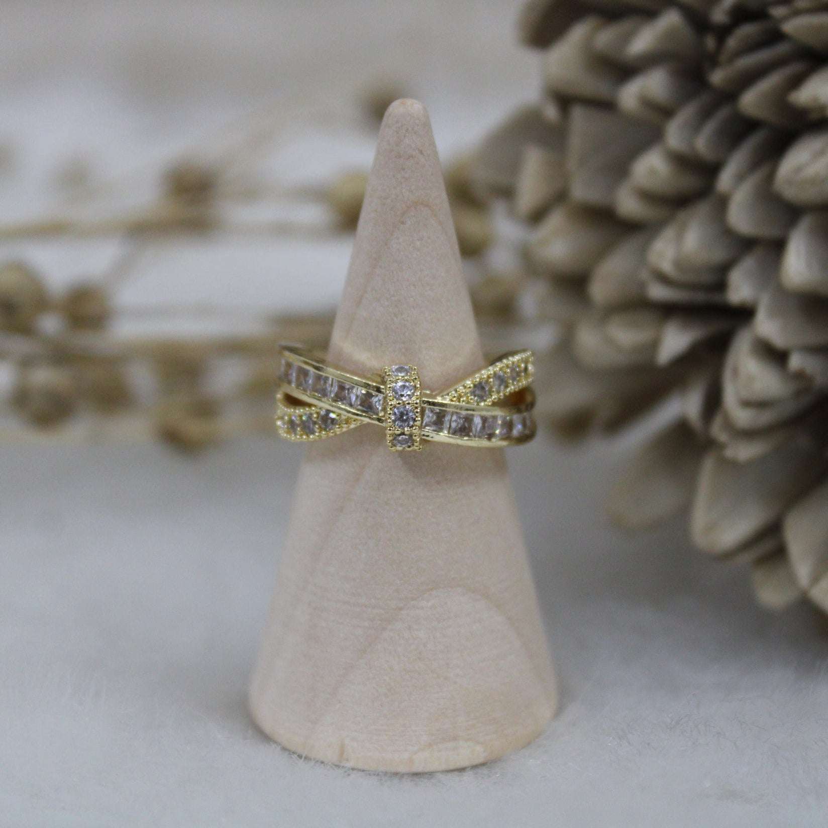 Gold ring with diamond accents on a wooden cone against a natural background