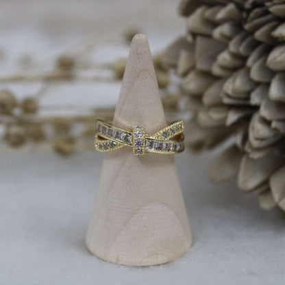 Gold ring with diamond accents on a wooden cone against a natural background