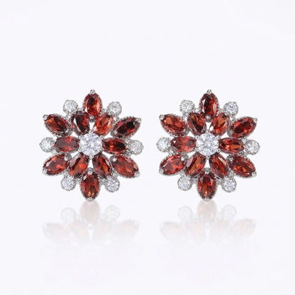 Pair of ruby red flower-shaped earrings with gemstones on a white background