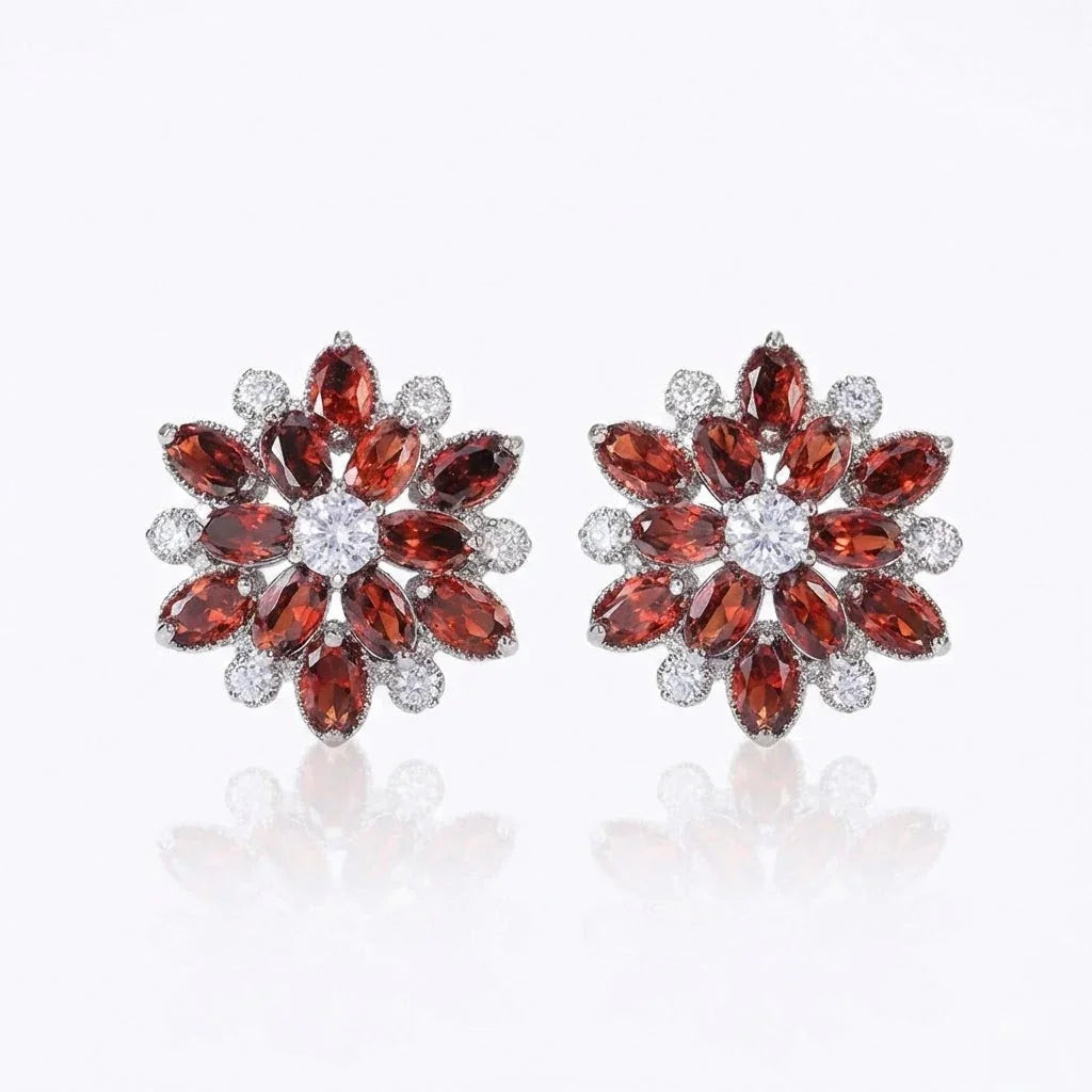 Pair of ruby red flower-shaped earrings with gemstones on a white background