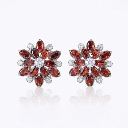 Pair of ruby red flower-shaped earrings with gemstones on a white background
