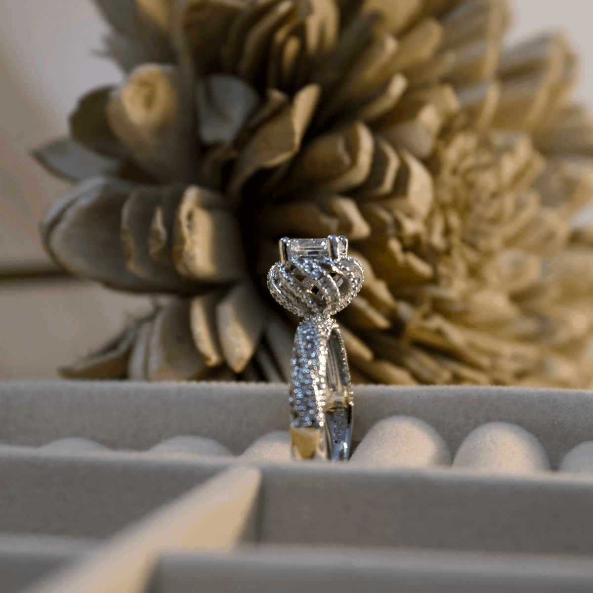 Diamond ring in a box with decorative flowers in the background