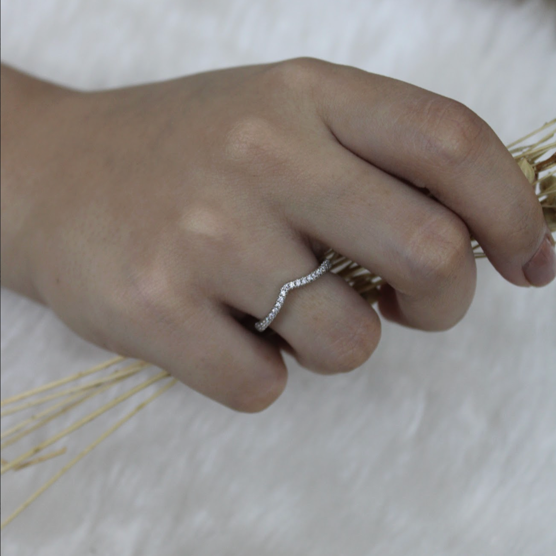 Hand wearing a silver ring on a light background