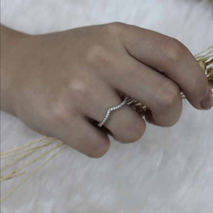 Hand wearing a silver ring on a light background