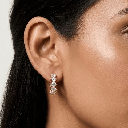 Close-up of a woman wearing diamond earrings with a neutral background